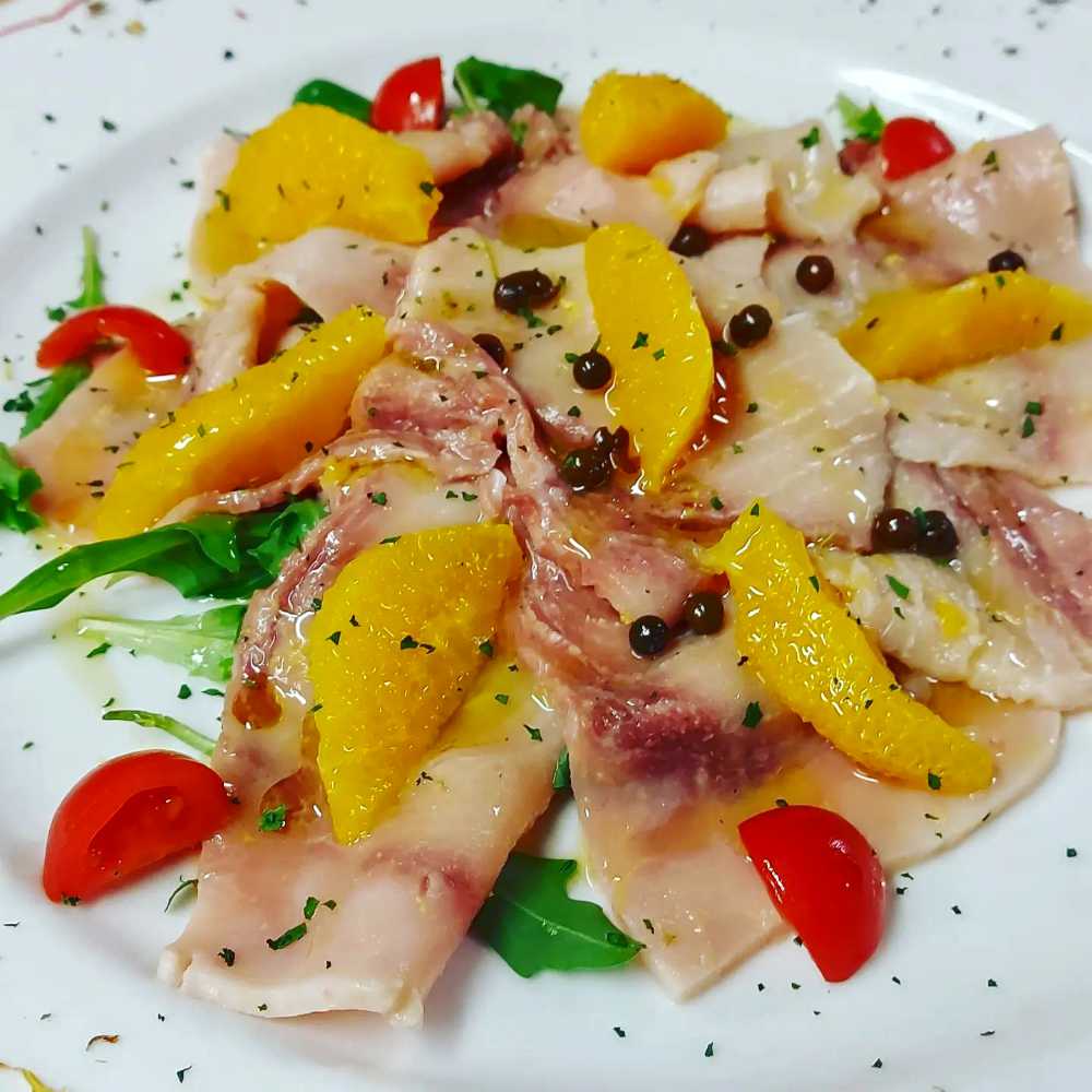 Carpaccio di Pesce Spada su lettino di Misticanza con Spicchi di Arancia, Pomodorini,Pepe in grani, Profumo di Lime