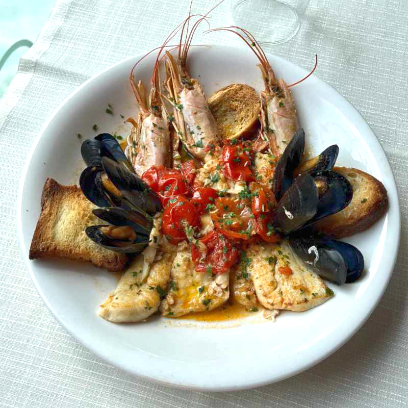 Orata, gamberi e cozze in guazzetto con pane tostato.